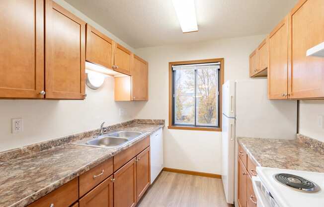 an empty kitchen with wooden cabinets and granite counter tops. Fargo, ND Flagstone Apartments
