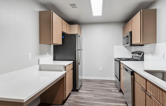 an empty kitchen with white countertops and a stainless steel refrigerator