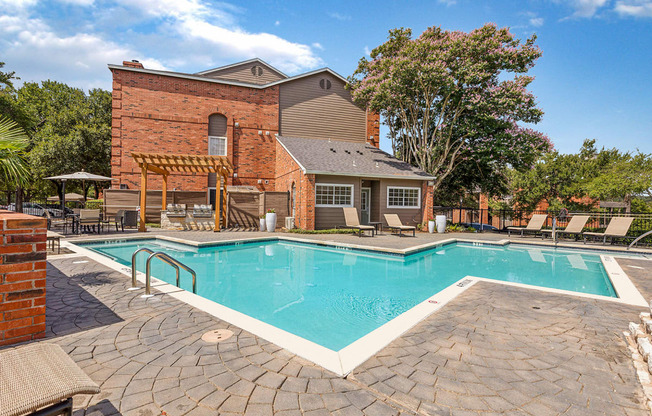 A pool surrounded by a brick wall and patio furniture.