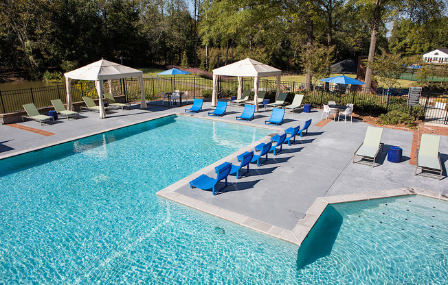 a swimming pool with blue lounge chairs and umbrellas