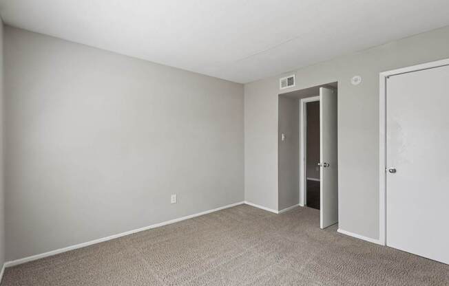 A room with a carpeted floor and two doors.