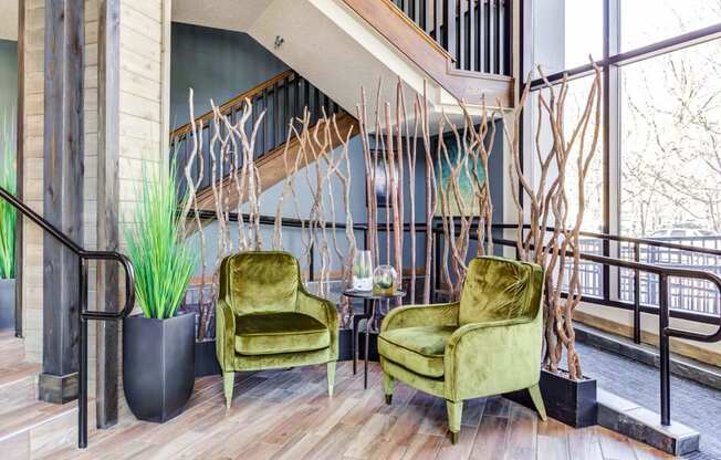 two green chairs in a lobby with a staircase in the background