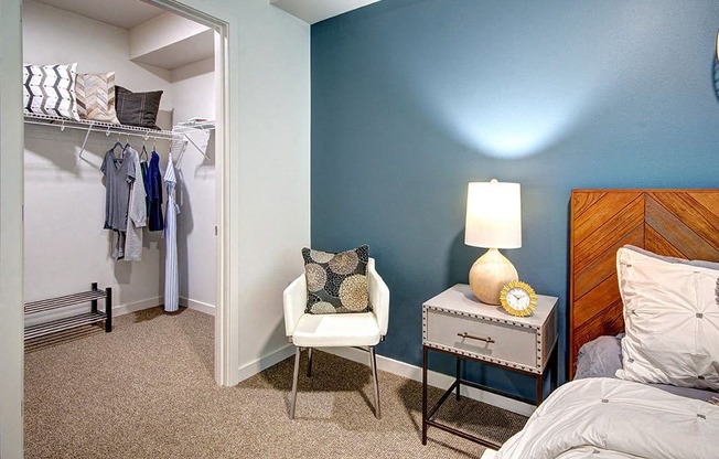 A bedroom with a bed, nightstand, chair, and closet. at Ravello Apartments, Redmond