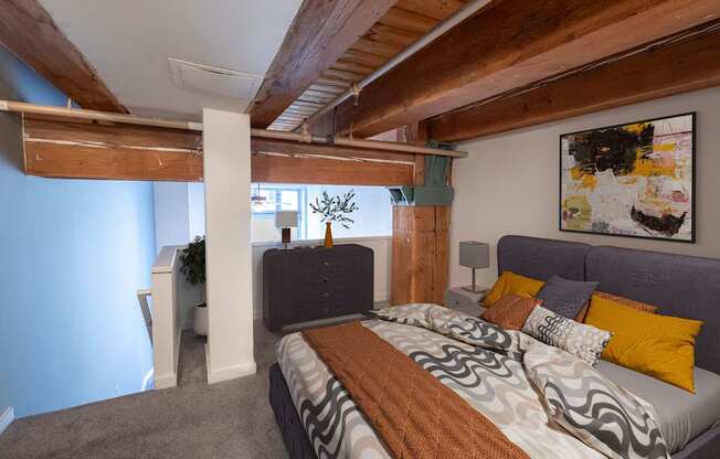 a bedroom with a bed and a couch in a room with exposed beams at Lowertown Commons Apartments, Minnesota