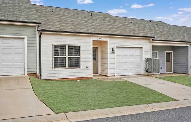 A row of houses with garages and a green lawn in front.