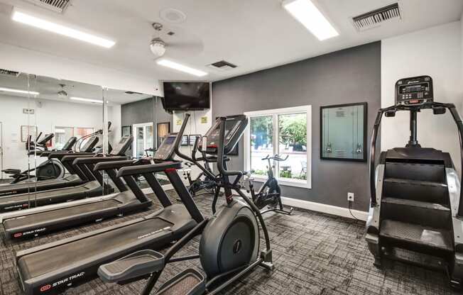 the gym is equipped with cardio equipment and weights at the enclave at university crossings apartments