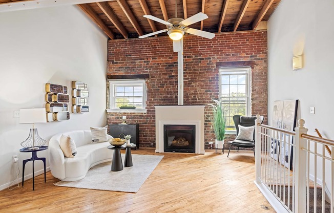 a living room with a ceiling fan and a brick fireplace