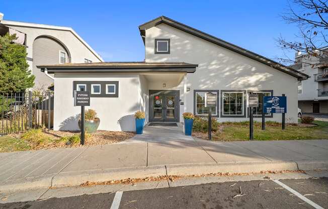 A white building with a black awning and a sign that says "Parking Only" in front of it.