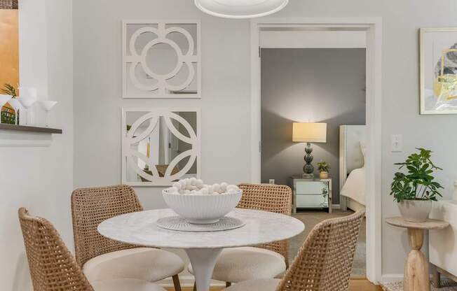 A white bowl is on a white table with four chairs around it.