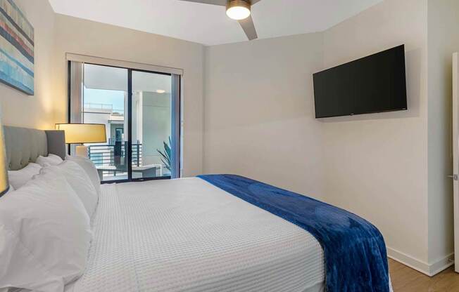 A bedroom with a large bed and a flat screen TV mounted on the wall.