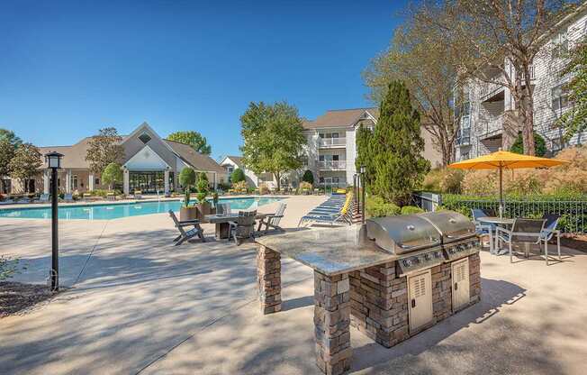 A poolside area with a stone BBQ and chairs.