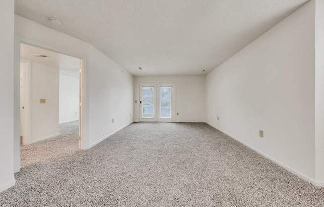 A spacious room with a carpeted floor and a door at the end.