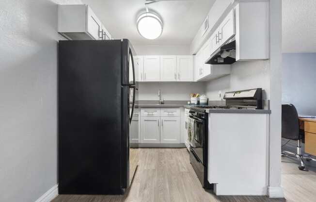 a kitchen with white cabinets and a black refrigerator