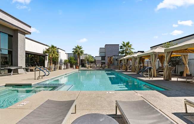 a swimming pool with tables and chairs next to a building