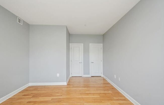 a bedroom with grey walls and a wooden floor