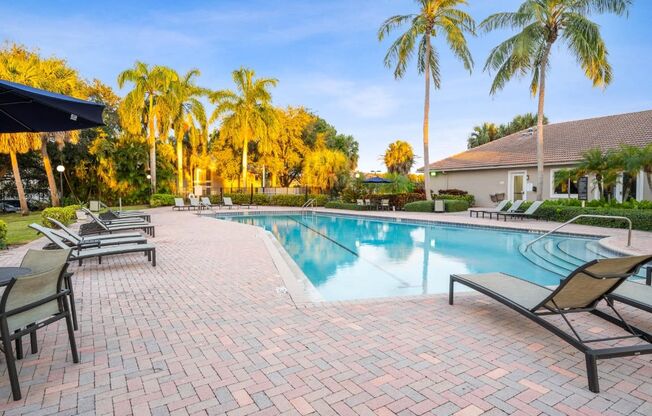 a swimming pool with chairs and palm trees