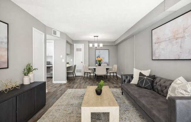 A living room with a grey couch, a coffee table, and a dining table with chairs.