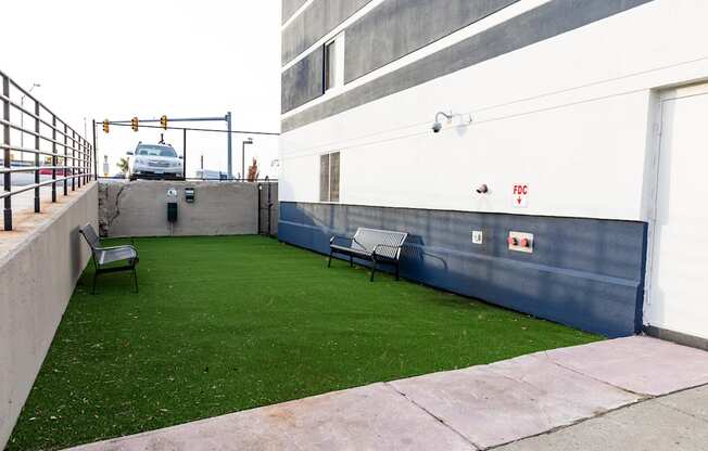 a yard with green grass and benches next to a building