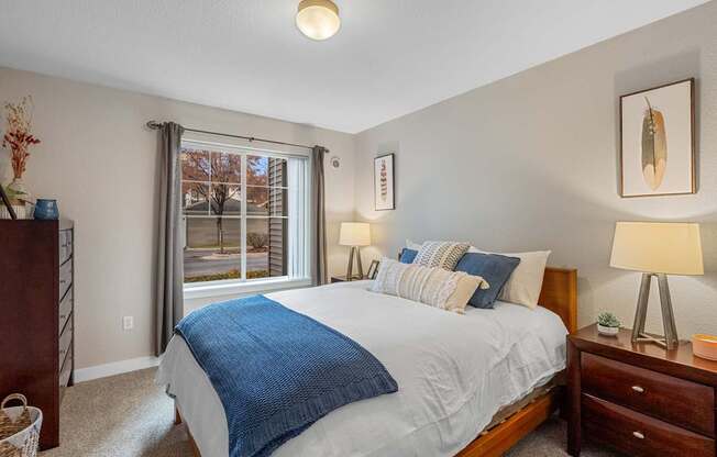 A bedroom with a bed, nightstands, and a window with a view of a tree.