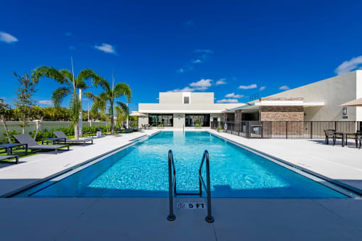 a swimming pool in front of a white building with palm trees the gym  at a residential apartment community Resia in Decatur GA