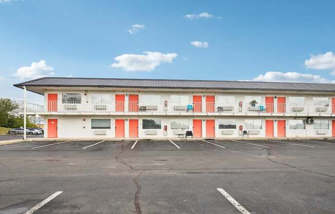 A parking lot in front of a building with red and white doors.
