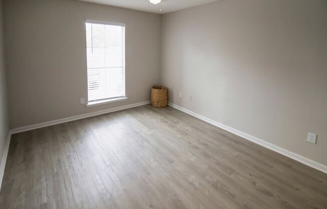 an empty living room with wood floors and a window