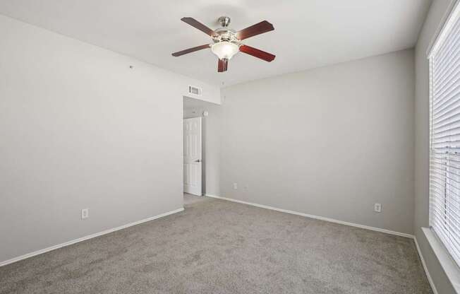 A room with a ceiling fan and carpeted floor.
