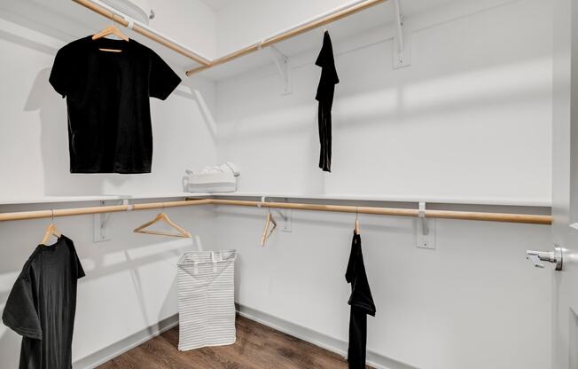a walk in closet with white walls and a wooden rod with clothes hanging on it at Prism at Diamond Ridge, Moon Township, PA, 15108