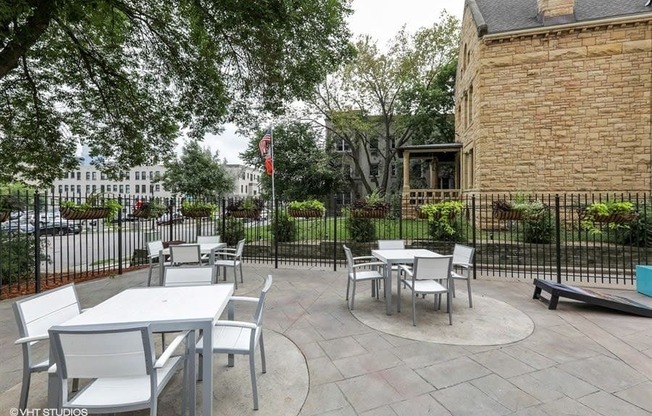 a patio with tables and chairs in front of a brick building