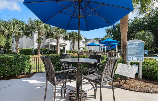 A blue umbrella is over a table with chairs around it.