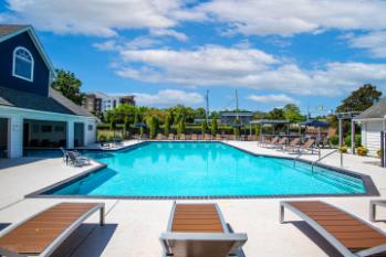 A large swimming pool with sun loungers in front of a building.