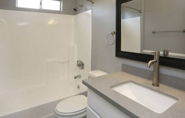 A bathroom with a toilet, sink, and mirror.