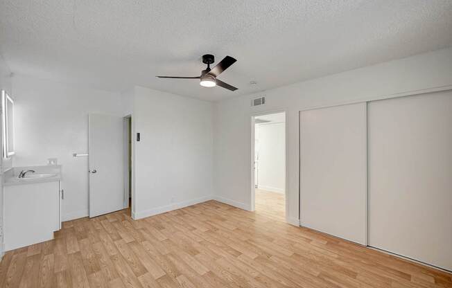A room with a ceiling fan and wooden flooring.