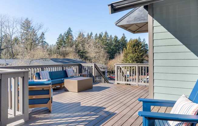 A wooden deck with blue chairs and a white railing.