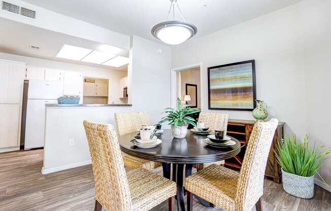 A dining room with a table set for two and a painting on the wall.