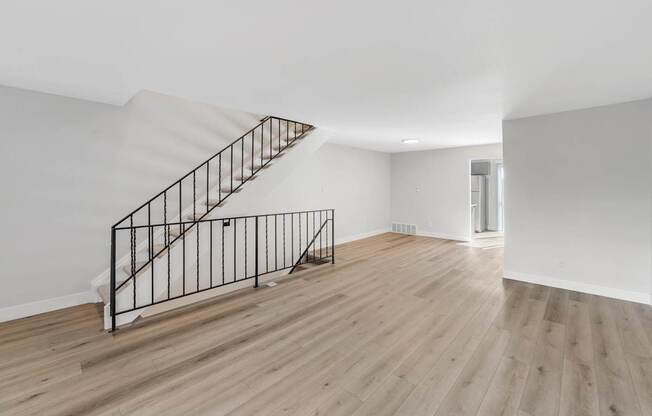 A wooden staircase with a metal railing leads to a second floor.