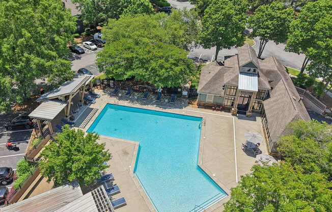 A large swimming pool surrounded by trees and a building.