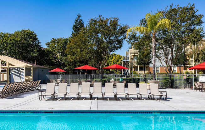 A pool with chairs and umbrellas in front of a building.