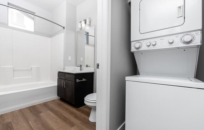 a white washer and dryer in a bathroom with a toilet and a sink