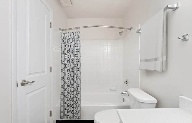 A white bathroom with a toilet, sink, and shower.