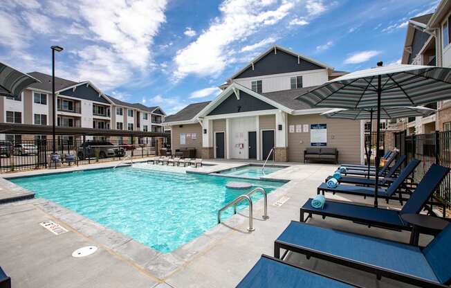 A swimming pool surrounded by lounge chairs and umbrellas.