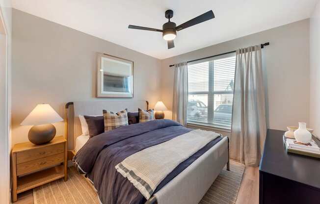 A bedroom with a bed, nightstand, and window.