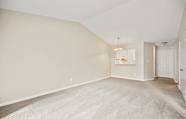 A large, empty room with a carpeted floor and a chandelier hanging from the ceiling.