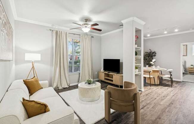 A living room with a white couch, a brown chair, and a television.