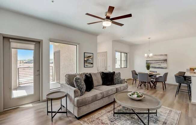 A living room with a grey couch and a ceiling fan.