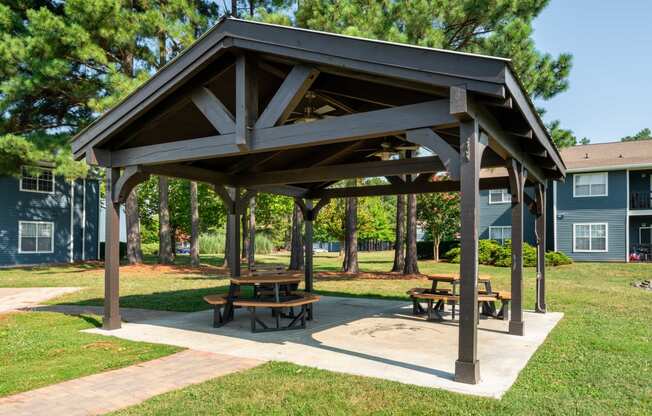 a picnic shelter with two picnic tables in a park