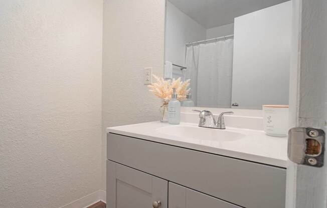 A white bathroom sink with a vase of flowers on top.