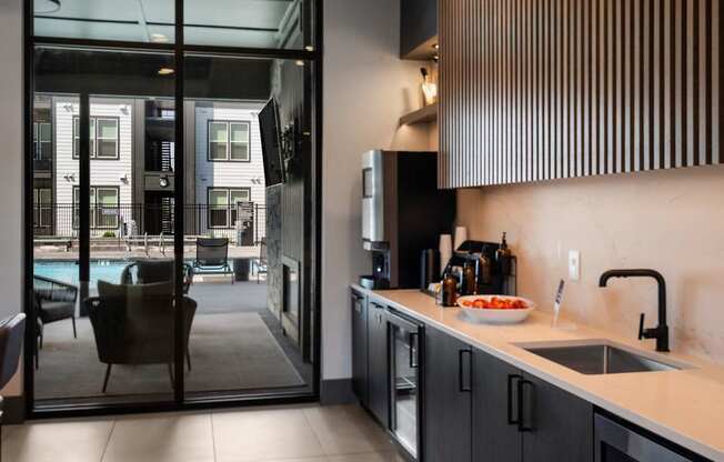 A modern kitchen with a view of a pool and apartment building.