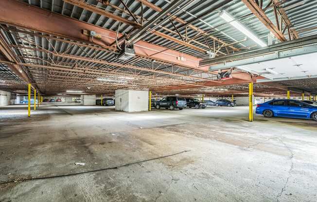A blue car is parked in a large, empty parking garage.