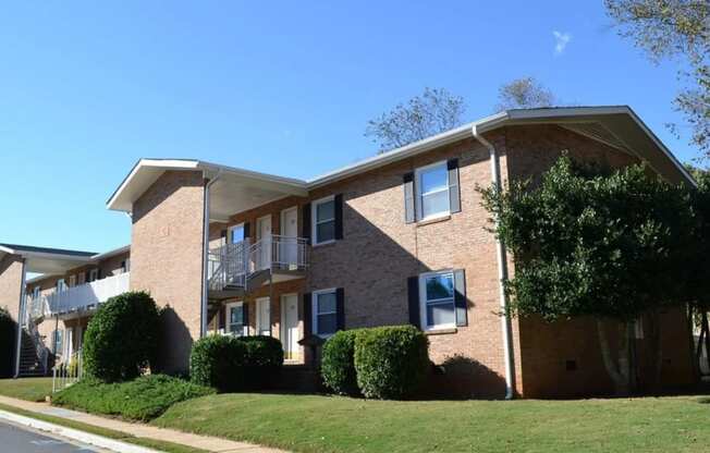 a brick apartment building with a lawn in front of it